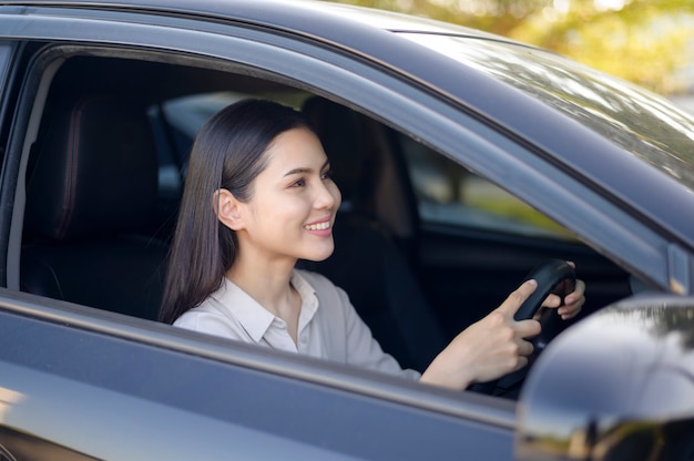 Une belle jeune femme souriante au volant de son concept de voiture, assurance et finance