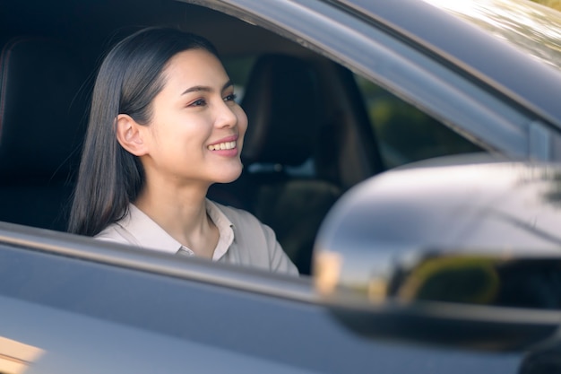 Une belle jeune femme souriante au volant de son concept de voiture, assurance et finance