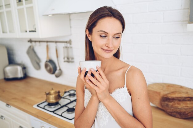 Belle jeune femme souriante, boire du café du matin.