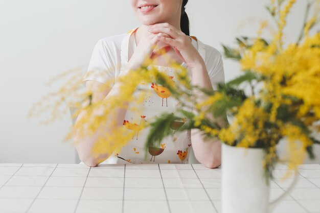 Belle jeune femme souriante avec des fleurs de mimosa sur fond blanc