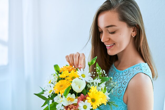 Belle jeune femme souriante heureuse avec fleur fraîche lumineuse colorée décorative