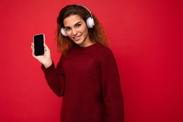 Belle jeune femme souriante et heureuse portant une tenue décontractée élégante isolée sur le mur de fond