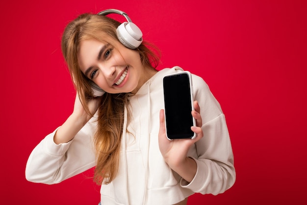 Belle jeune femme souriante et heureuse portant une tenue décontractée élégante isolée sur le mur de fond