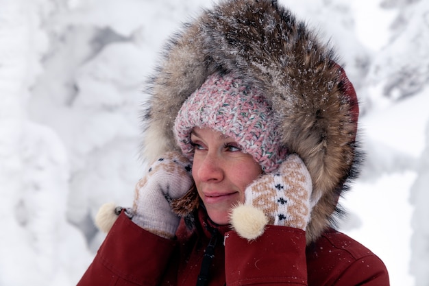 Belle jeune femme souriante à la recherche sur le côté en bonnet rose avec pompon en veste chaude à l'extérieur