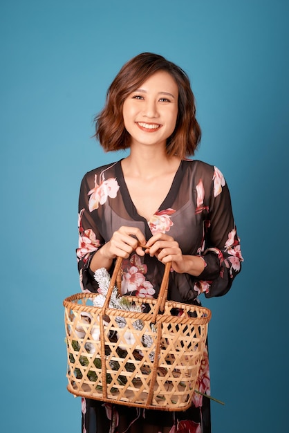 Belle jeune femme souriante en robe vintage tenant un panier avec des fleurs Portrait d'été jolie jeune fille