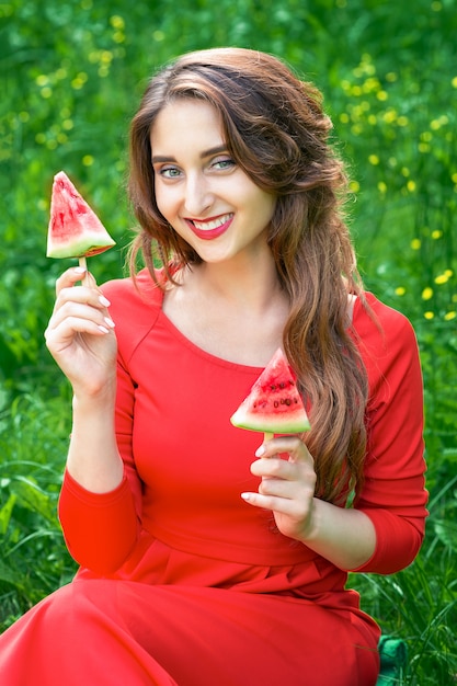 Belle jeune femme souriante tient deux tranches de pastèque sous forme de glace