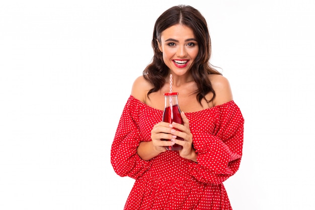 Belle jeune femme avec un sourire parfait boit du jus de fraise isolé