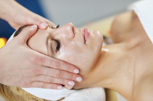 Belle jeune femme en spa et bien-être. Massage du visage et du dos aux pierres