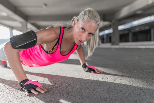 Belle jeune femme sportive faisant des push ups à l&#39;extérieur.