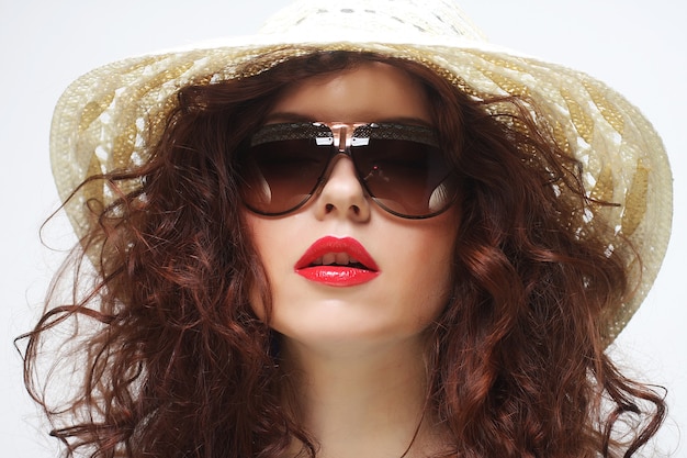 Belle jeune femme surprise portant un chapeau et des lunettes de soleil