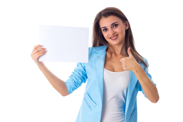 Belle jeune femme en T-shirt blanc et veste bleue tenant une feuille de papier blanche en studio