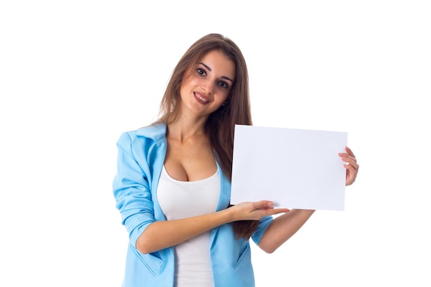 Belle jeune femme en T-shirt blanc et veste bleue tenant une feuille de papier blanche en studio