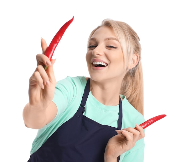 Belle jeune femme en tablier et avec des piments sur une surface blanche