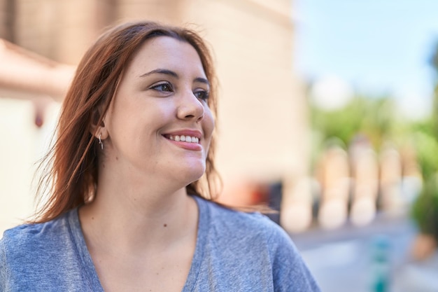 Belle jeune femme de taille plus souriante confiante regardant sur le côté dans la rue