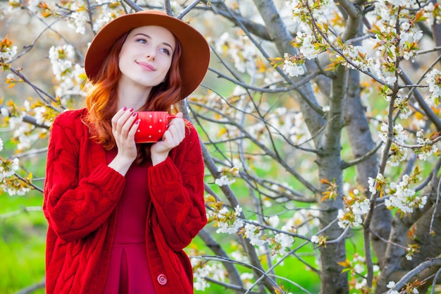 belle jeune femme avec une tasse de café sur le magnifique fond d&#39;arbres fleurissant