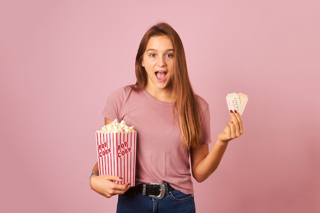 Belle jeune femme tenant des billets de pop-corn et de cinéma