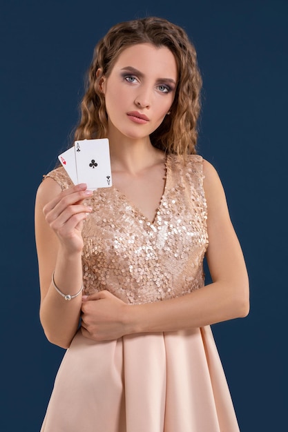 Belle jeune femme tenant la combinaison gagnante de cartes de poker sur fond bleu foncé. deux as