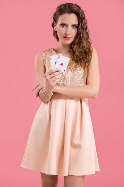 Belle jeune femme tenant la combinaison gagnante de cartes de poker sur fond rose. deux as