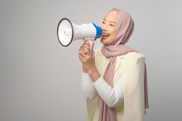 Belle jeune femme tenant un mégaphone sur fond blanc studiox9