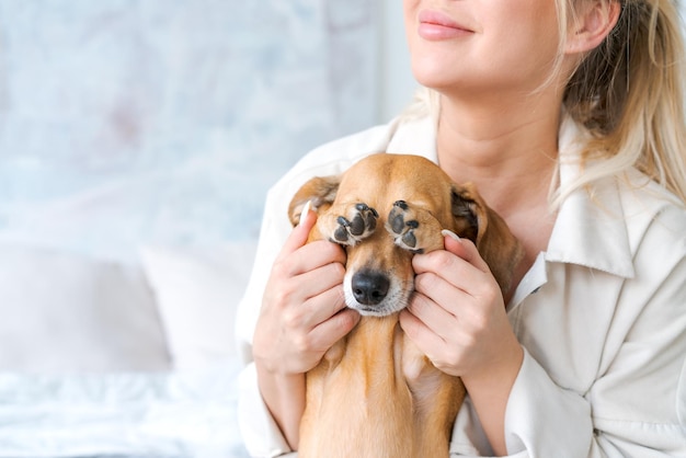 Une belle jeune femme en tenue décontractée embrasse et caresse son chien bien-aimé assis