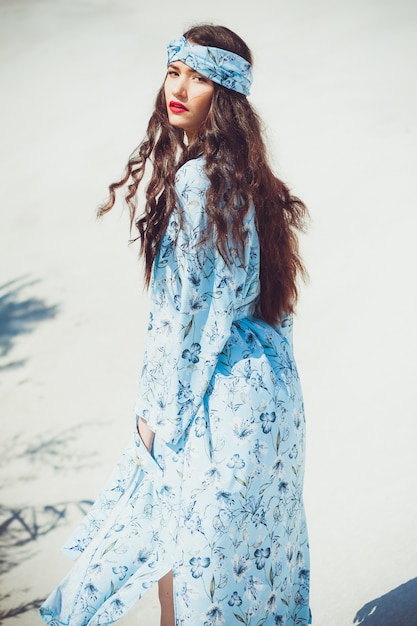 Belle jeune femme en tenue de plage se promène sur le sable