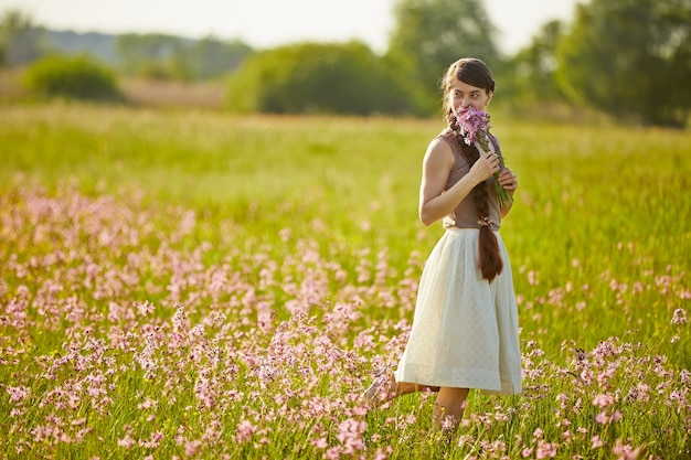 Belle jeune femme sur le terrain avec des fleurs