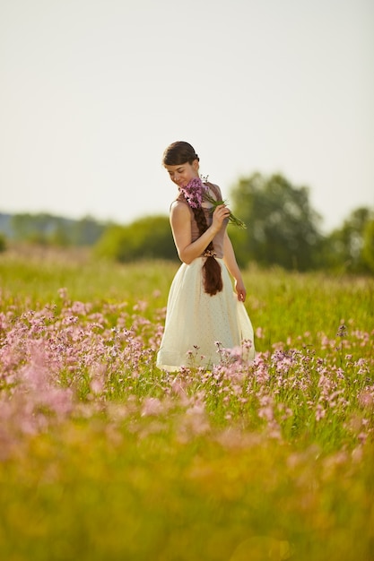 Belle jeune femme sur le terrain avec des fleurs