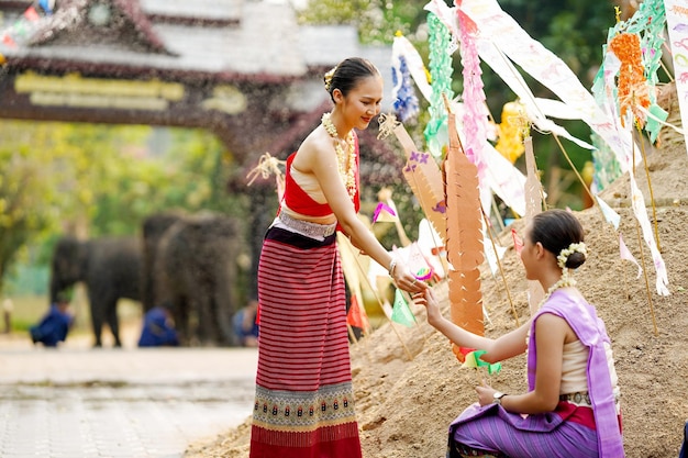 Une belle jeune femme thaïlandaise donne un petit drapeau de papier à ses amis pour les aider à placer dans le sable