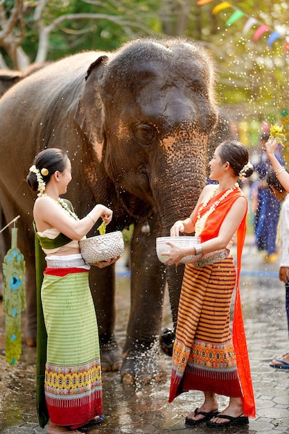 Une belle jeune femme thaïlandaise s'habille en robe traditionnelle et utilise des fleurs pour arroser de l'eau le jour de Songkran.