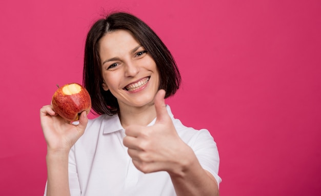 Belle jeune femme tient une grosse pomme dans sa main