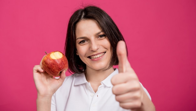 Belle jeune femme tient une grosse pomme dans sa main