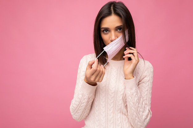 Belle jeune femme tient et porte un masque médical blanc pour se protéger du virus corona