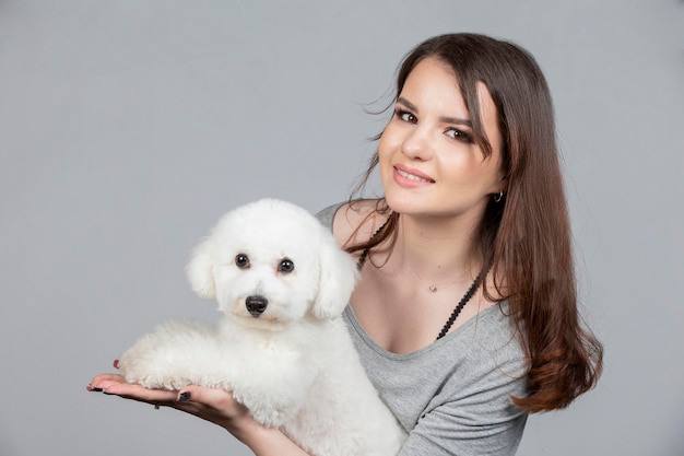 Une belle jeune femme tient son chiot bichon