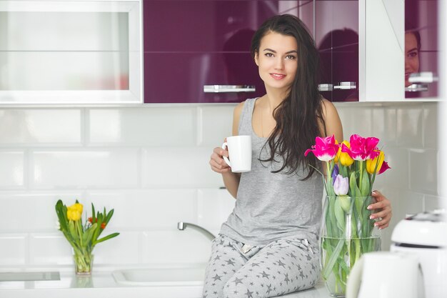 Belle jeune femme tôt le matin, prendre un café dans la cuisine. Matin frais. Boisson vivifiante. Honoraires de travail. Réveillez-vous madame.