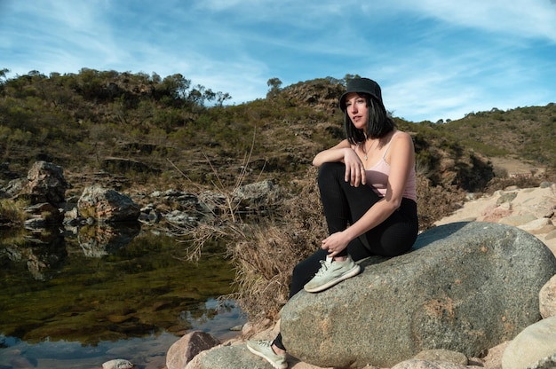 Belle jeune femme touristique reposant assise sur un rocher au milieu des montagnes