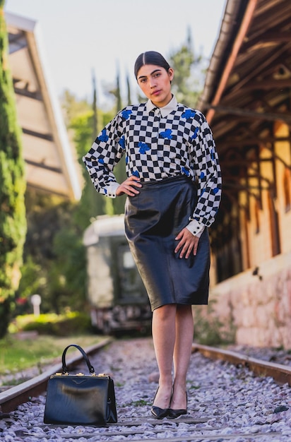 Belle jeune femme touristique de style rétro dans l'ancienne gare, vêtue d'une veste jaune et noire.