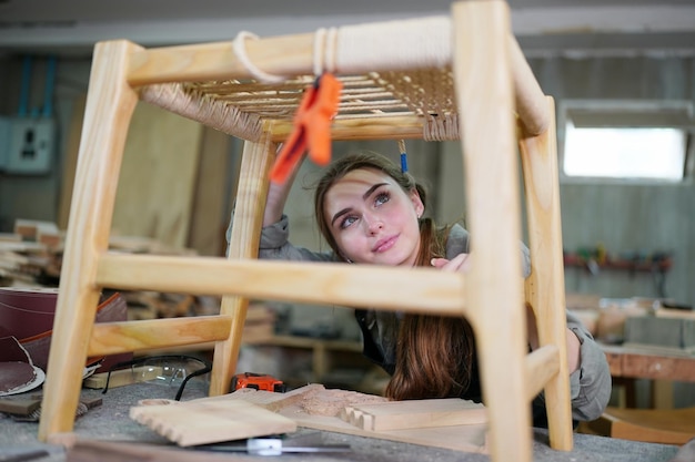 Belle jeune femme travaillant dans la salle de l'atelier de menuiserie bricolage. Propriétaire d'une petite entreprise, jeune femme qui travaille dans une usine de meubles.