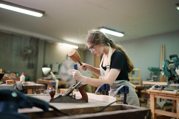 Belle jeune femme travaillant dans la salle de l'atelier de menuiserie bricolage. Propriétaire d'une petite entreprise, jeune femme qui travaille dans une usine de meubles.
