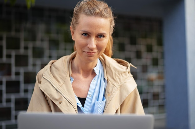 Belle jeune femme travaillant sur un ordinateur portable assis sur le banc dans la rue