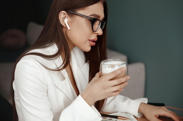 Belle jeune femme travaillant sur un ordinateur portable en buvant du café