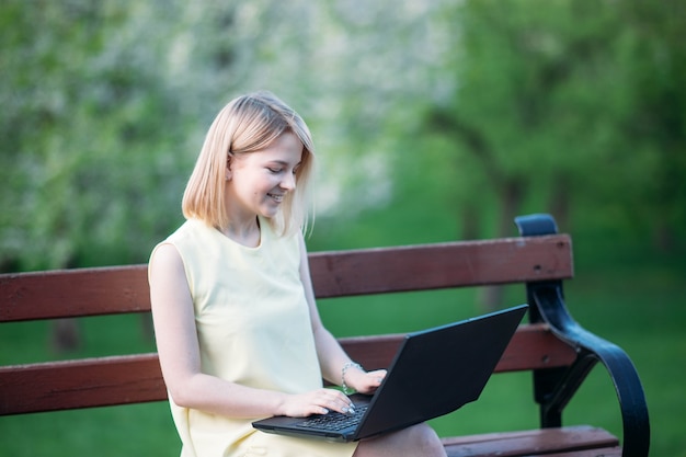 belle jeune femme travaillant sur ordinateur portable dans le parc fille pigiste dans la nature