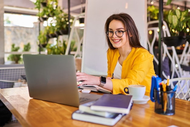 Belle jeune femme travaille au bureau avec ordinateur portable.