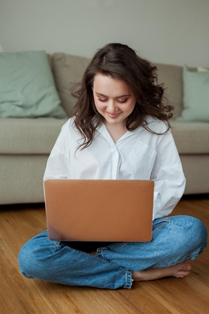 Belle jeune femme travaille en ligne à la maison avec un ordinateur portable Bureau à domicile Étudier en ligne Médias sociaux Conversation vidéo Maison confortable