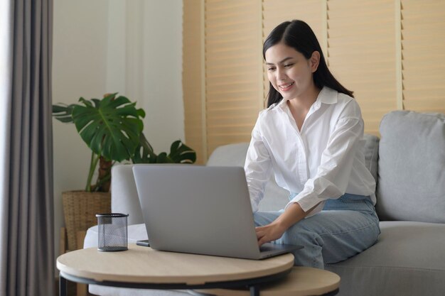 Belle jeune femme travaille avec son ordinateur à la maison