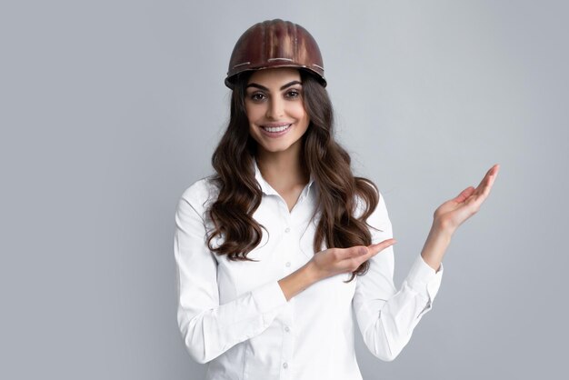 Belle jeune femme travailleuse en casque isolé sur fond gris