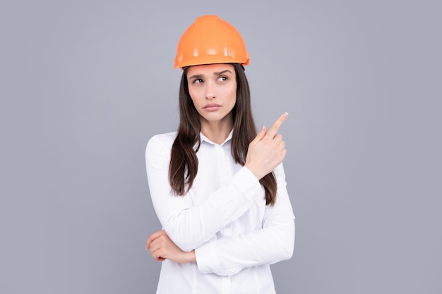 Belle jeune femme travailleuse en casque isolé sur fond gris