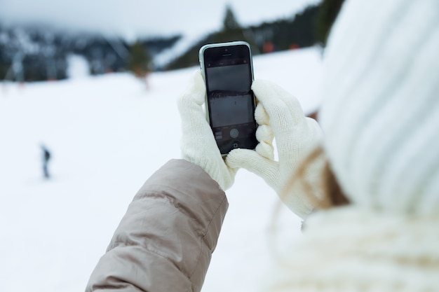 Belle jeune femme utilisant son téléphone mobile sur fond d&#39;hiver.