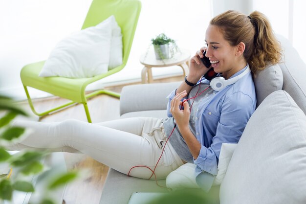 Belle jeune femme utilisant son téléphone mobile à la maison.