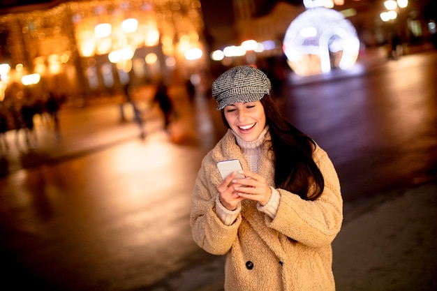 Belle jeune femme utilisant son téléphone portable dans la rue au moment de Noël