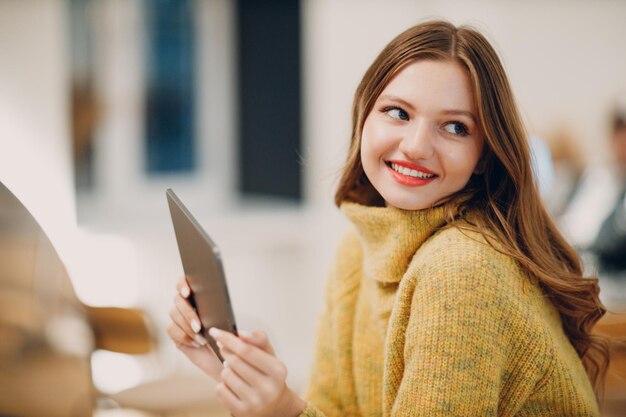 Belle jeune femme utilisant une tablette numérique à une table de café avec une tasse de café